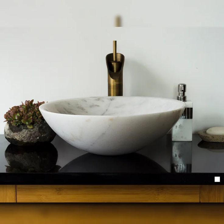 a white bowl sink sitting on top of a black counter