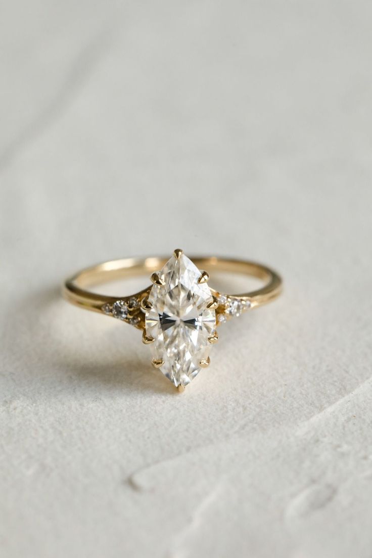 an engagement ring with three stones on the front and side, set in yellow gold