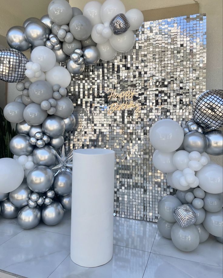 silver and white balloons are on display in front of a mirror wall with disco balls