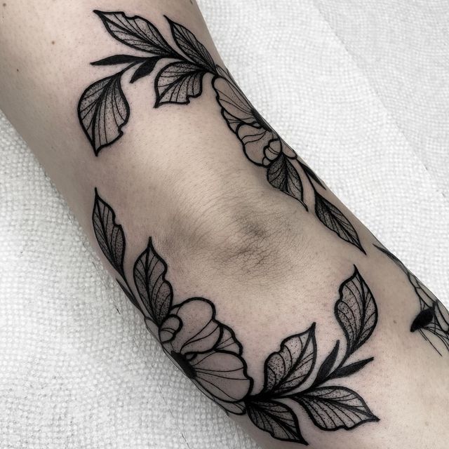 a black and white photo of a flower on the left arm with leaves around it