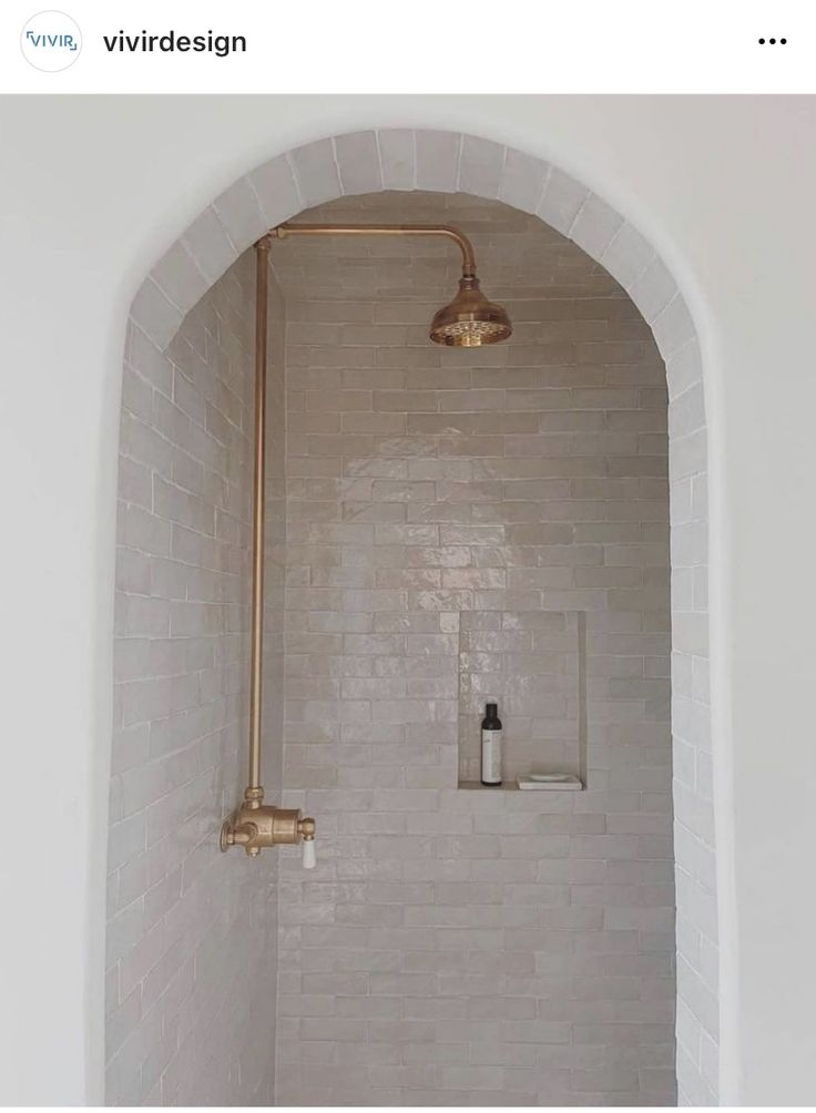 a bathroom with a shower, toilet and bathtub in it's corner next to a brick wall