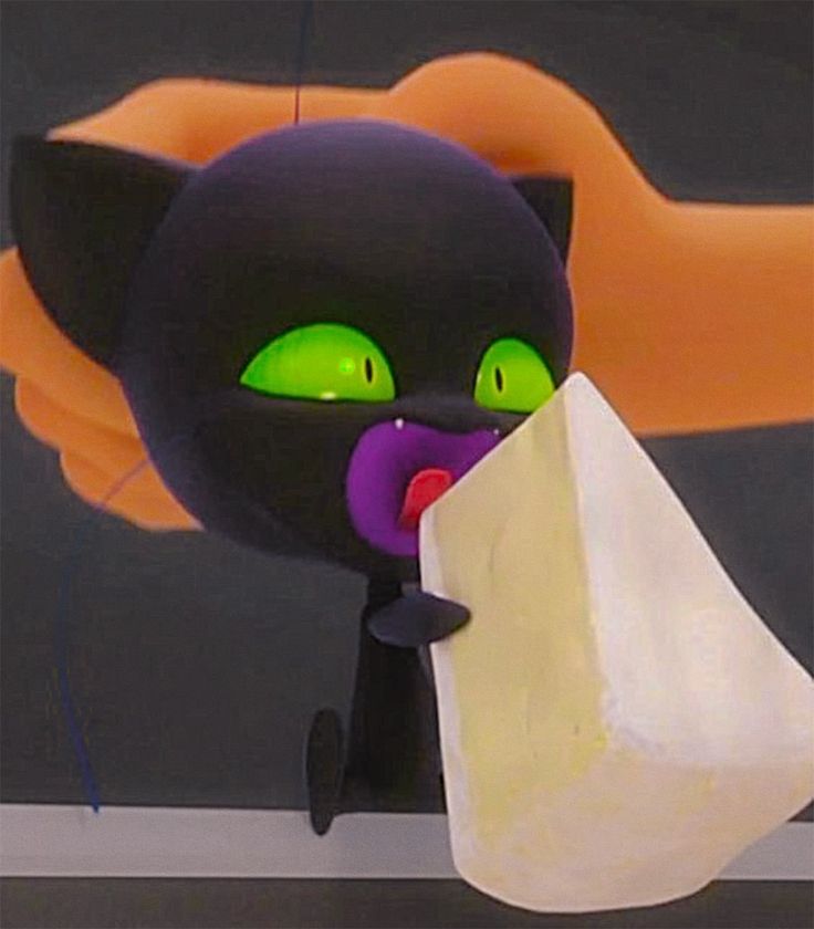 a black cat with green eyes holding a piece of paper in it's mouth