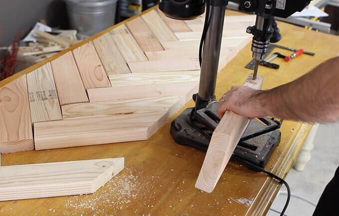 a person using a drill to cut wood planks on a workbench with a machine