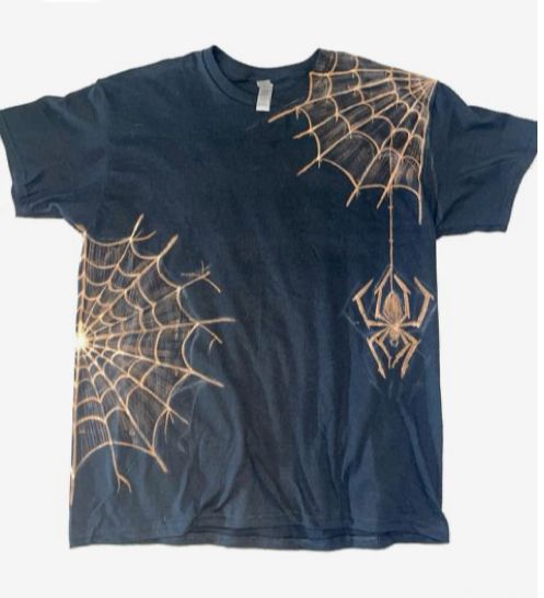 a black t - shirt with gold spider webs on it