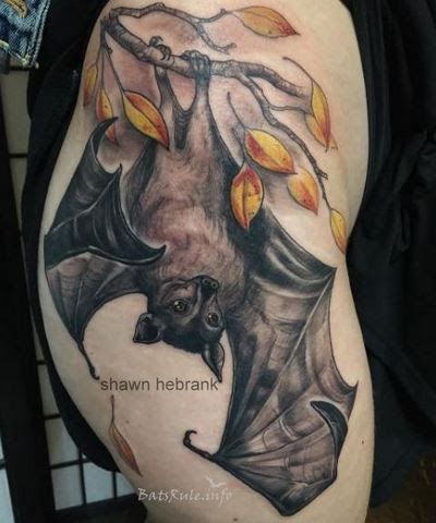 a bat tattoo on the side of a woman's thigh