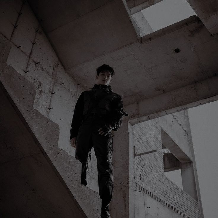 a young man standing on top of a cement structure with his hands in his pockets