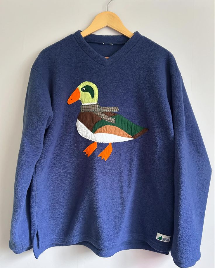 a blue sweater with a green duck on it