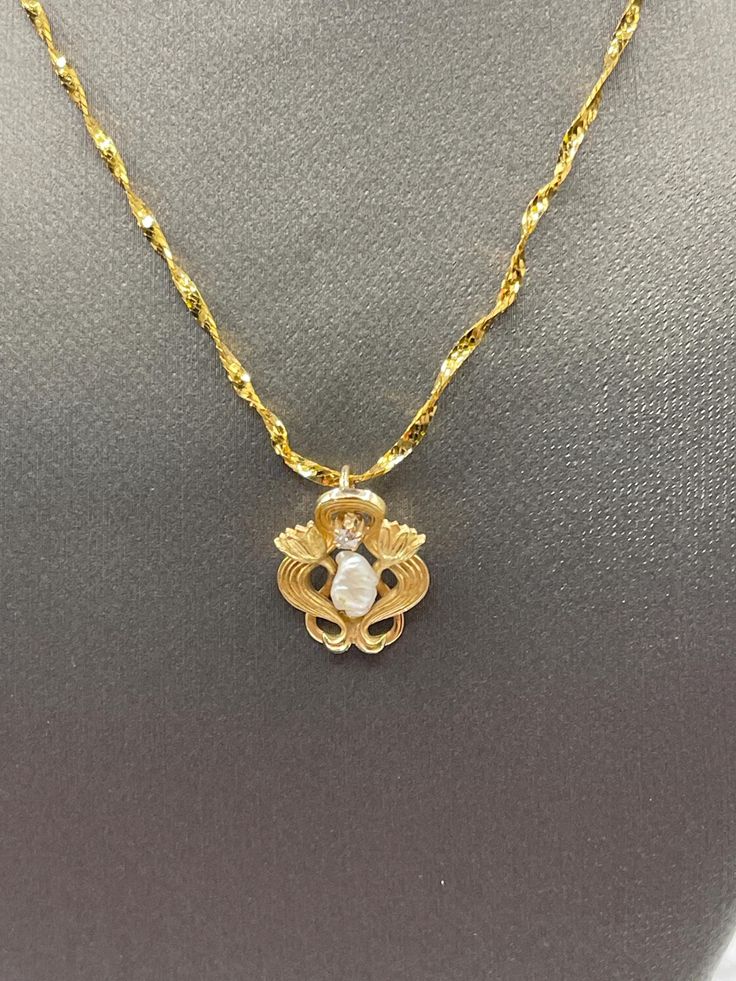 A lovely antique made in 14 karat solid yellow gold. A unique necklace offers exquisite detailed craftsmanship.  A freshwater Pearl and round white diamond adorn the center of this beautiful pendant, which hangs from a beautiful twisted sparkle chain.  A beautiful and feminine necklace. Weight:  3.2 grams Length:  16" Our Price $395.00 Regularly Priced At $600.00 Please See Our Video Remember - If you're purchasing for yourself or a gift for a loved one, buy with confidence.  We Guarantee Everyt Antique White Gold Necklace With Pearl Pendant, Vintage Diamond Necklace In Yellow Gold, Antique Diamond Cut Pendant Necklace, Exquisite Gold Oval Diamond Necklace, Vintage Diamond White Pendant Necklace, Vintage Gold Diamond Necklaces, Gold-plated Flower Pendant With Pearl, Heirloom Pearl Pendant Necklace, Antique Yellow Gold Necklace With Diamond Accents