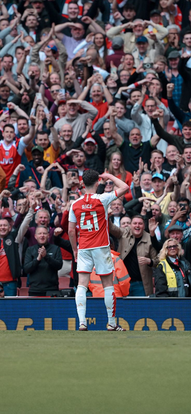 two soccer players are standing on the field with their arms in the air and fans behind them