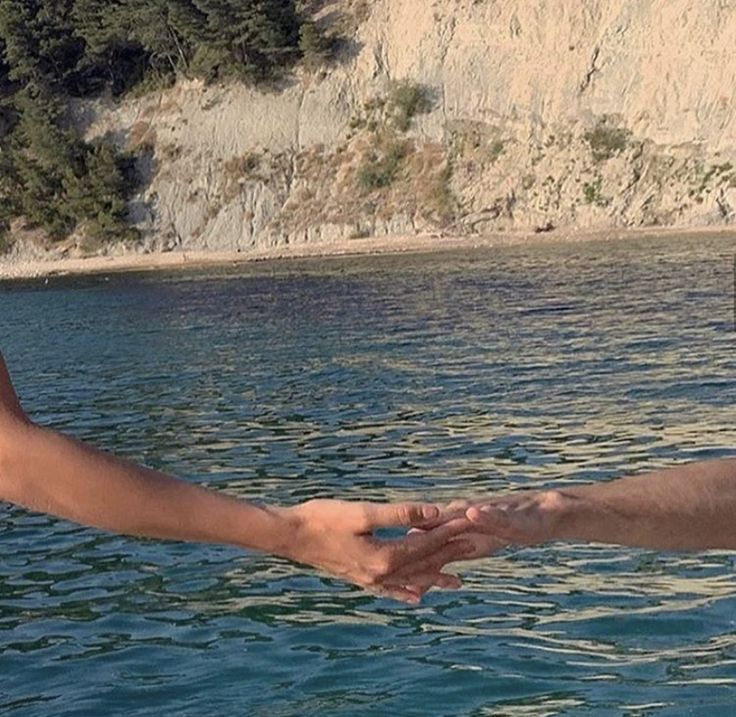 two people holding hands while standing on a boat