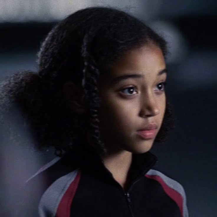 a close up of a person with braids on her hair looking at the camera