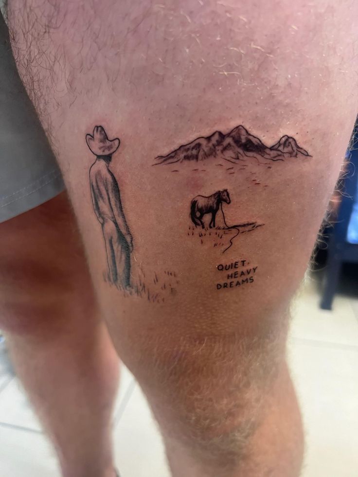 a man with a tattoo on his leg that has a horse and mountains in the background