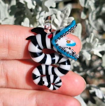 a hand holding a black and white zebra keychain with a blue bird on it