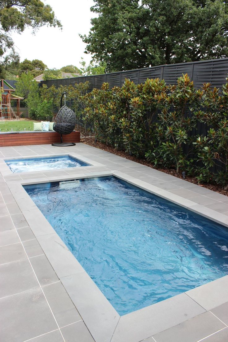 an empty swimming pool in the middle of a backyard with trees and bushes around it