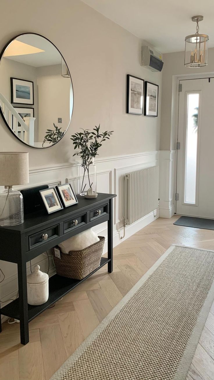 a living room with a black table, mirror and pictures on the wall above it