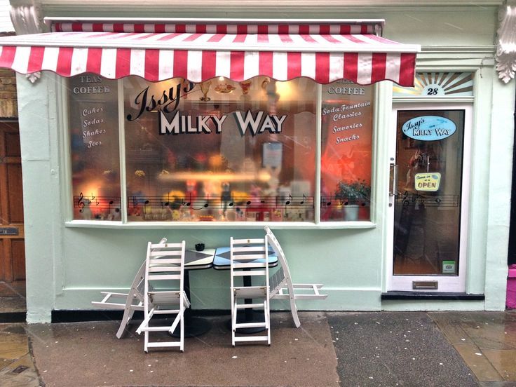 two chairs and a table in front of a store with a red and white awning