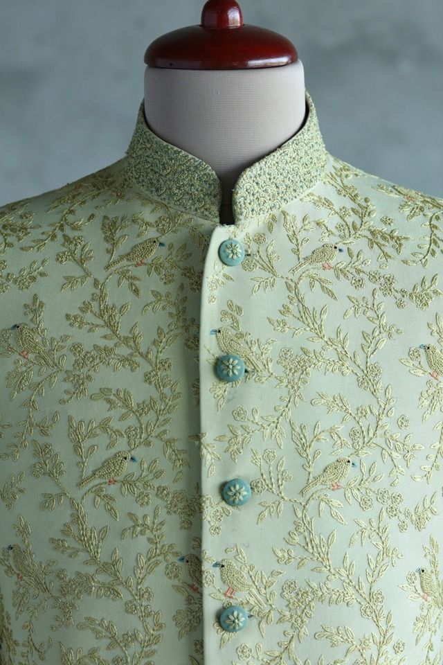 a mannequin wearing a green and gold brocaded shirt with buttons on the collar