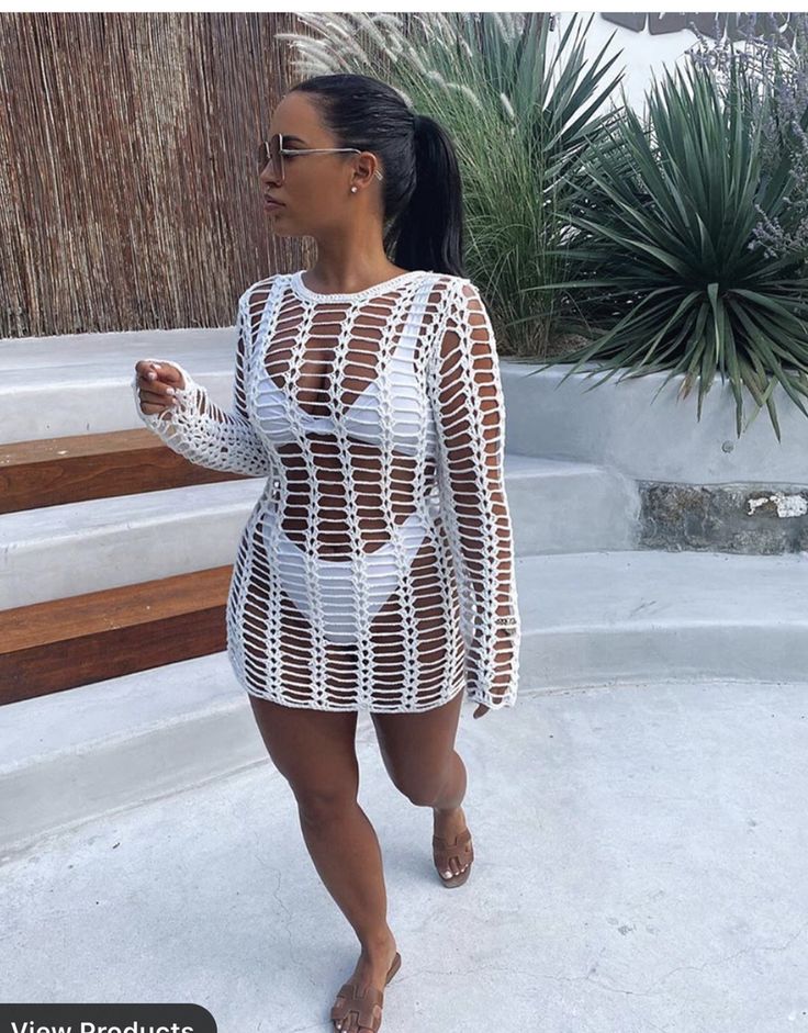 a woman wearing a white crochet bodysuit and sunglasses walking down the street