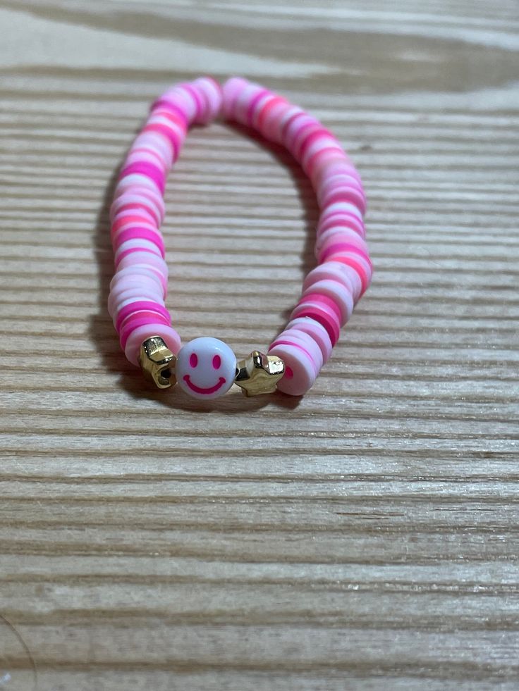 a pink and white beaded bracelet with smiley face beads on it's end