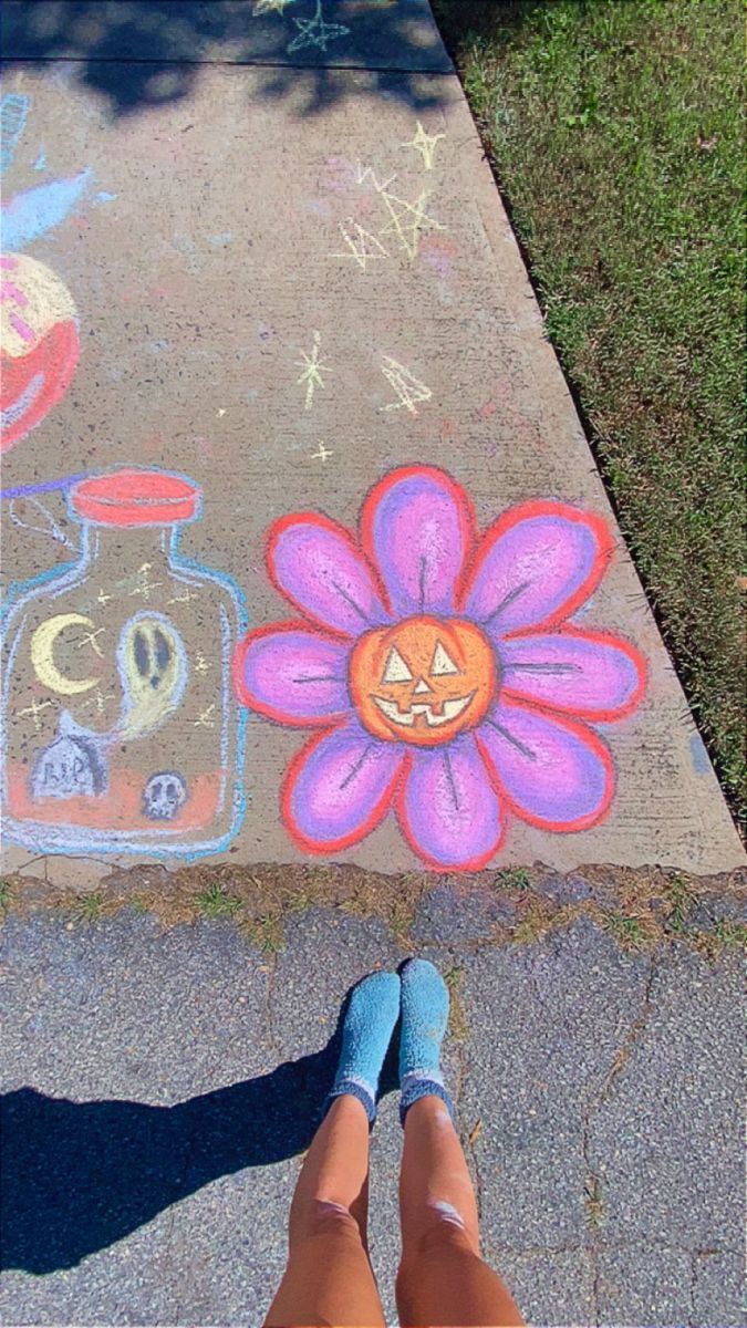 someone is standing on the sidewalk with their feet in front of chalk drawings and flowers