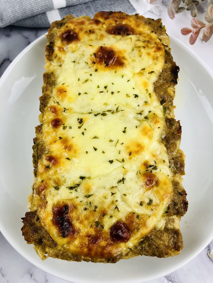 a white plate topped with an entree covered in cheese