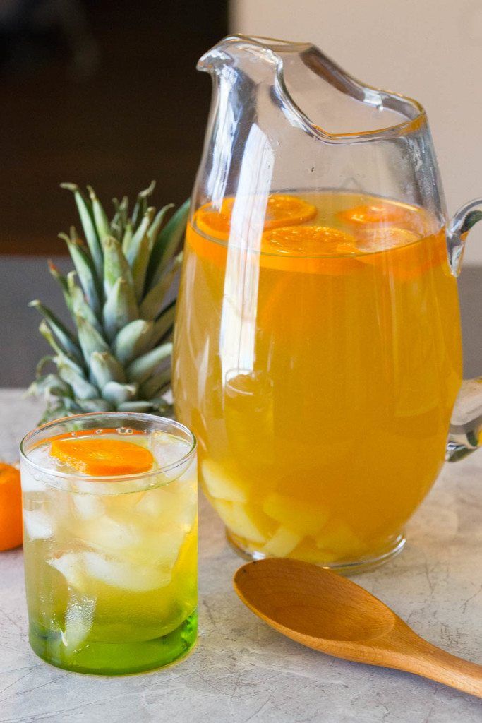 a pitcher of orange juice next to two glasses and a wooden spoon