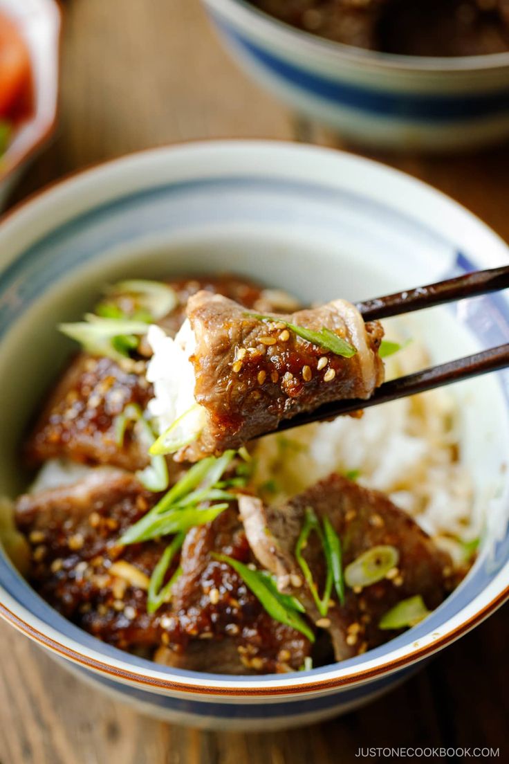 a close up of a bowl of food with chopsticks sticking out of it