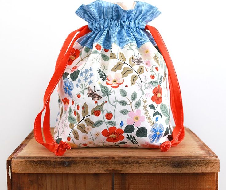 a drawstring bag sitting on top of a wooden table next to a white wall