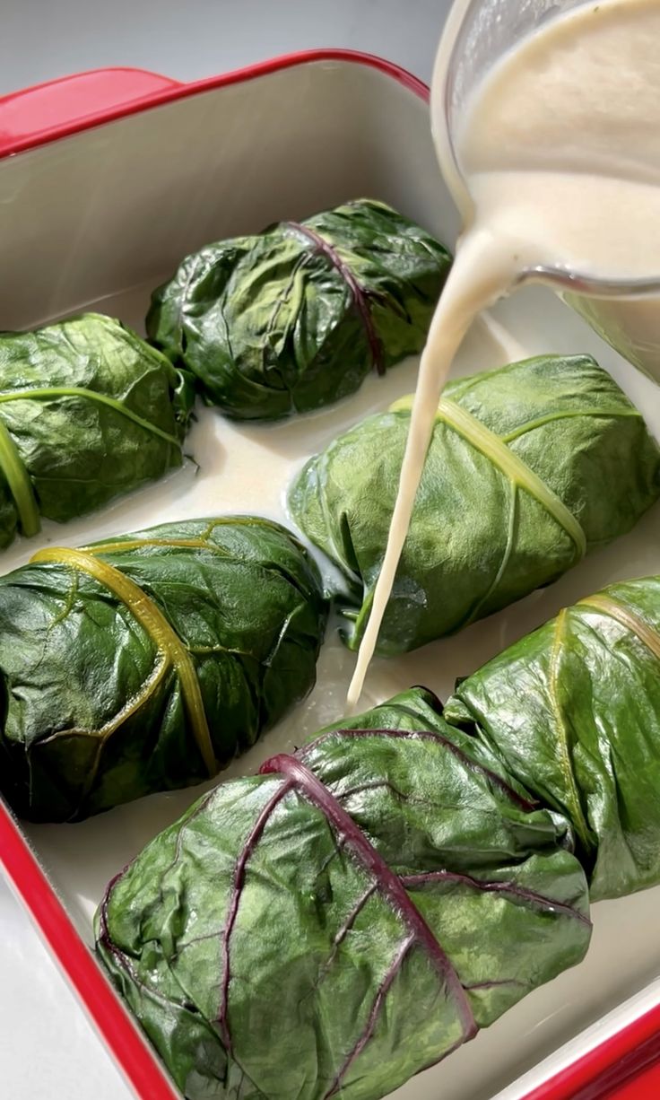 spinach rolls being poured with milk in a red container