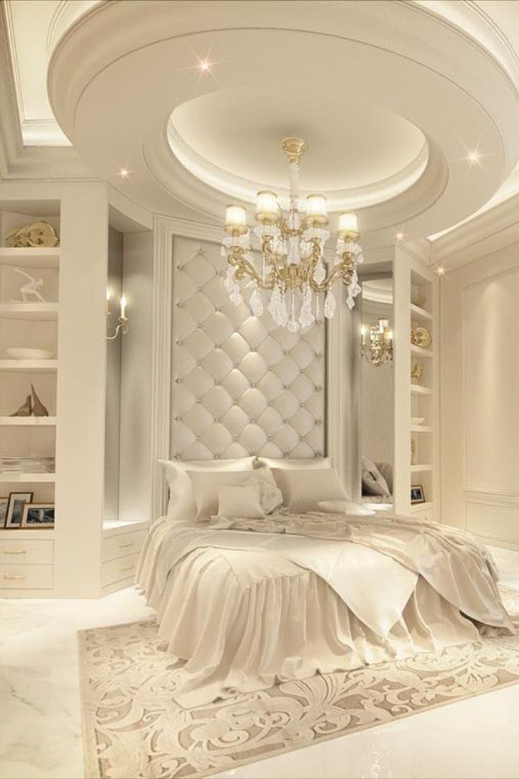 a large white bed sitting under a chandelier in a bedroom