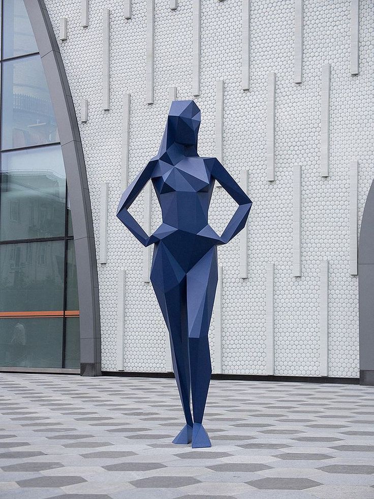 a blue sculpture stands in front of a building