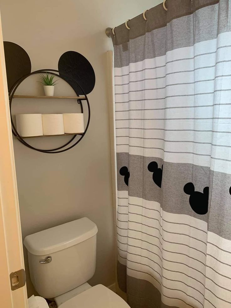 a bathroom with a mickey mouse shower curtain and toilet paper roll holder on the wall