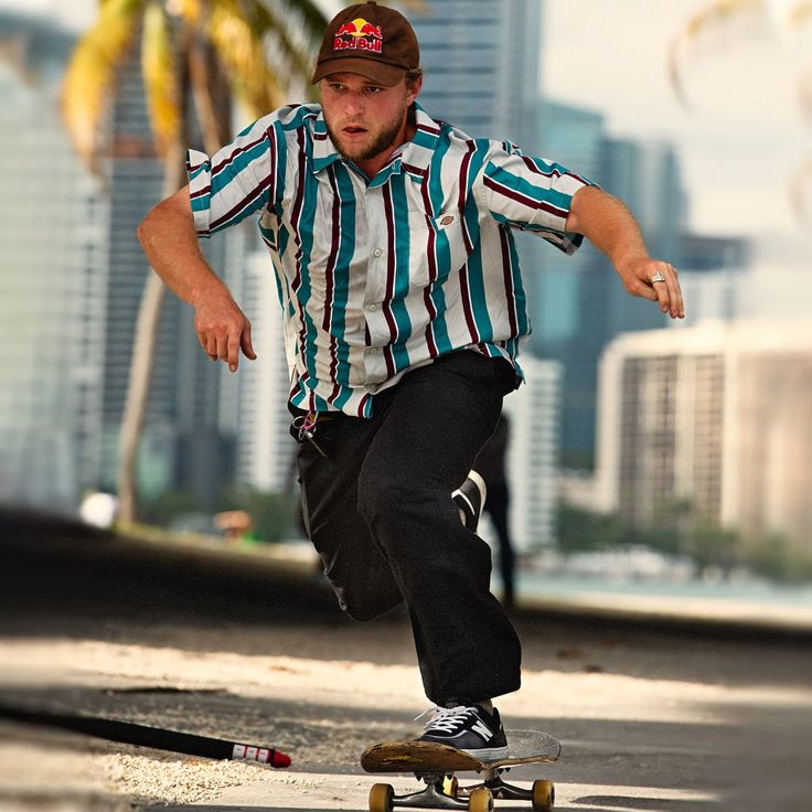 a man riding a skateboard down the side of a road next to tall buildings