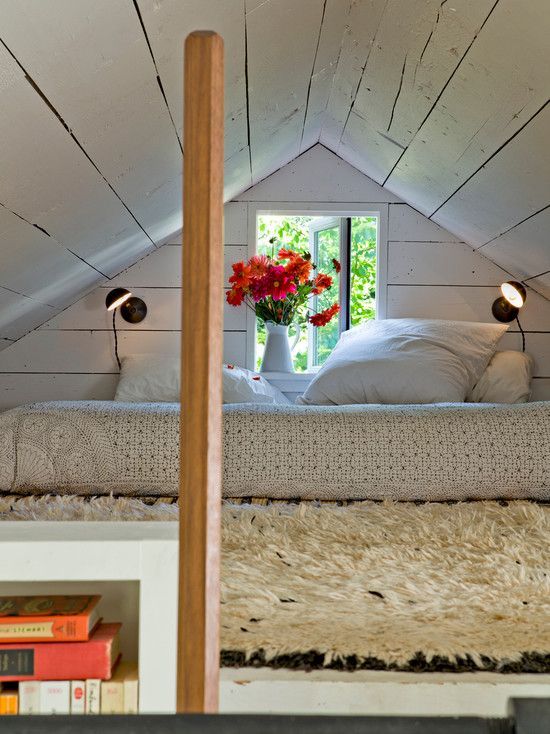 there is a bed with white sheets and pillows in the attic