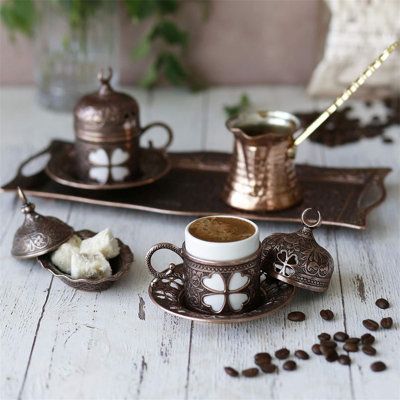 a coffee cup and saucer sitting on top of a tray next to some beans