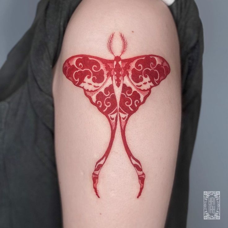 a woman's arm with a red butterfly tattoo on it