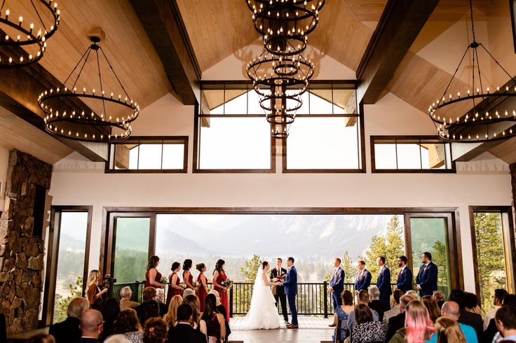 a bride and groom are standing in front of their wedding party at the top of a mountain