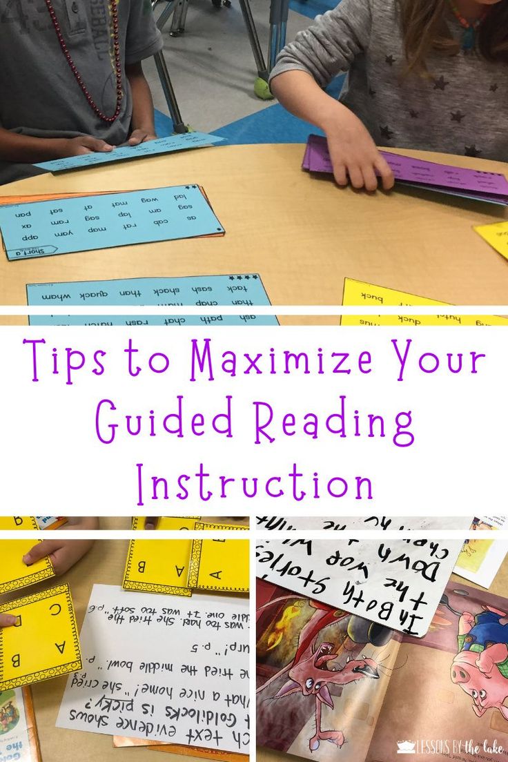 two children are sitting at a table with their hands on the paper and one child is reading