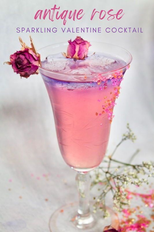 a pink cocktail in a glass with flowers on the rim