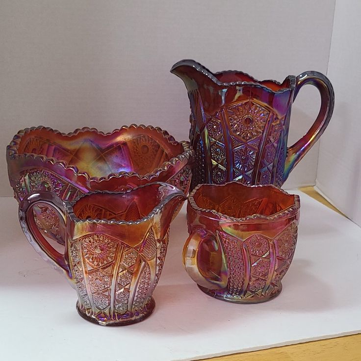 three glass vases sitting on top of a white table next to each other in front of a wall