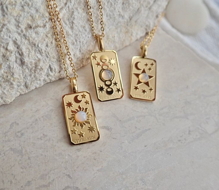 We're so excited to introduce my new line of high quality, anti-tarnish, waterproof jewelry. Thanks to our special plating technique, this celestial beauty is built to last, both pendant and chain are anti tarnish and waterproof. Crafted with hypoallergenic 18k gold stainless steel, it's lead and nickel free and safe and comfortable for sensitive skin. Your choice of pendants feature three of my favorite Major Arcana cards and a sweet little faux opal cabochon for an added touch of mystery. Choo Celestial Stainless Steel Jewelry For Gifts, Celestial Gold Jewelry With Rectangular Pendant, Gold Celestial Jewelry With Rectangular Pendant, Celestial Style Tarnish Resistant Necklace As Gift, Celestial Tarnish-resistant Necklace As Gift, Celestial Rectangular Pendant Jewelry Gift, Celestial Style Tarnish-resistant Necklace For Gifts, Celestial Style Rectangular Pendant Jewelry Gift, Gold Celestial Hypoallergenic Jewelry