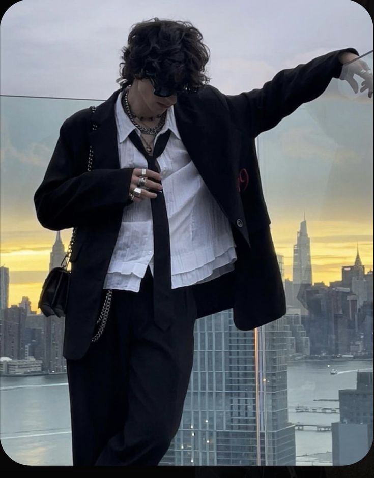 a man in a suit and tie standing on top of a building looking at his cell phone