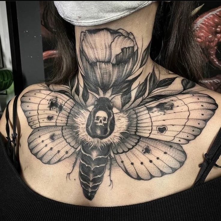 a woman with a black and white tattoo on her neck has a skull in the center