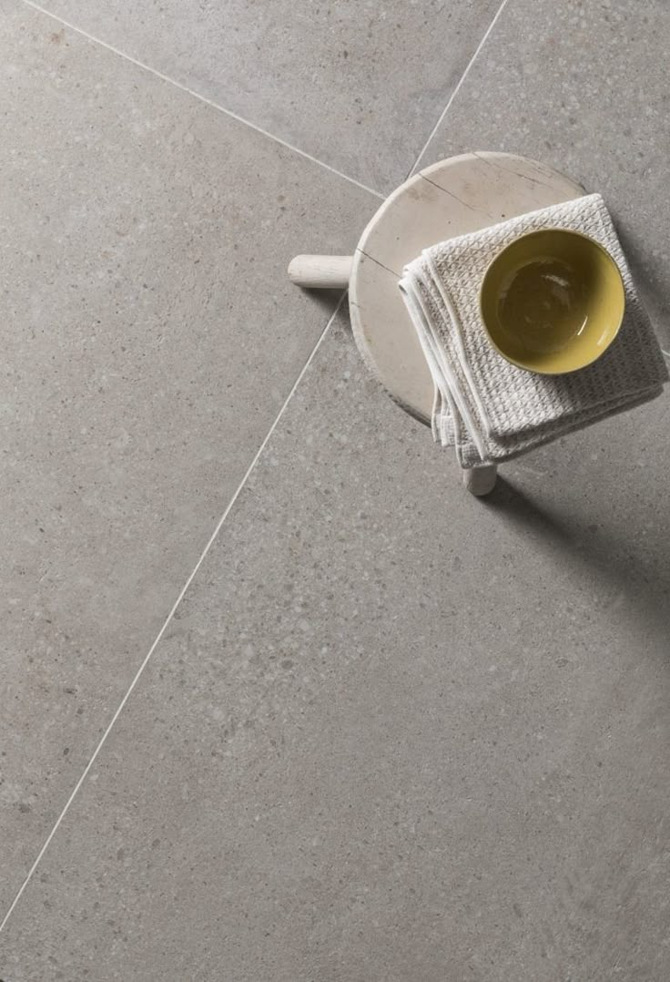 a yellow cup sitting on top of a white plate next to a gray tile floor