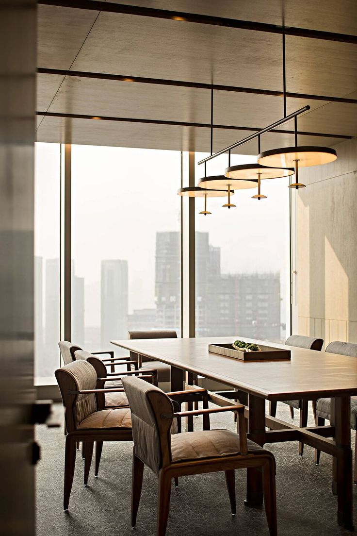 a dining room table and chairs in front of large windows