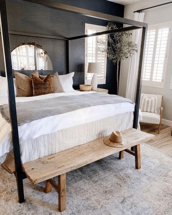 a bedroom with a four poster bed and wooden bench on the floor in front of it