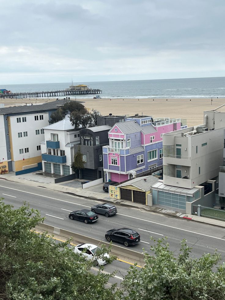 the beach is lined with colorful houses and parked cars in front of the oceanfront