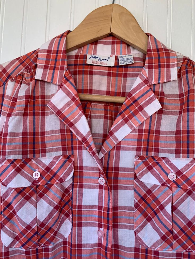 "NEW with original tags! Vintage Plaid Long Sleeve button up shirt Size 14 / Large - White Blue Red and Coral Plaid. Puff sleeves. Front pockets on chest. Autheintic vintage deadstock from the early 80s, New With Tags! Brand - Amy Barr 60% Cotton 40% Polyester Machine Washable Made in China Condition - Original Deadstock from the 80s, New With Tags Vintage Size - 14 Fits Like - large can fit smaller sizes with looser fit (see measurements) Measurements (Seam to seam, lying flat) - Bust* - 40\" W Plaid Cotton Collared Blouse, Red Camp Collar Shirt With Button Closure, Red Shirt With Camp Collar And Button Closure, Red Shirt With Button Closure And Camp Collar, Plaid Top With Button Closure And Spread Collar, Plaid Top With Spread Collar And Button Closure, Retro Red Tops With Pockets, Red Collared Blouse With Pockets, Red Tops With Button Closure And Spread Collar