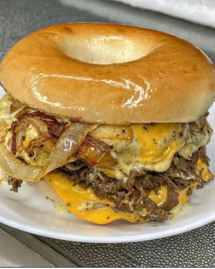 a bagel sandwich on a white plate with cheese and onions in the buns