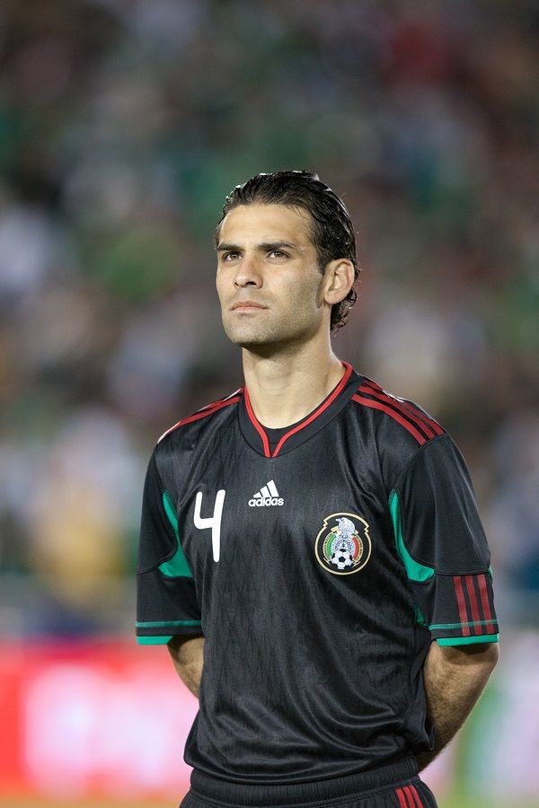 a soccer player standing on the field with his hands in his pockets and looking off into the distance